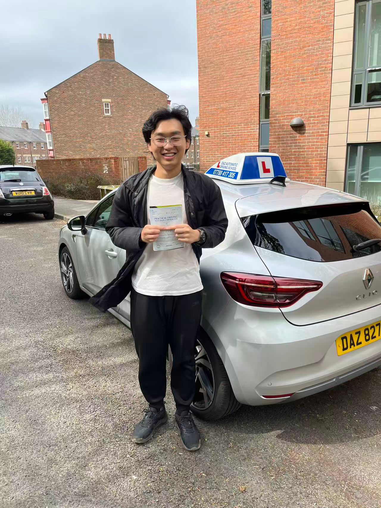 Pupil with pass certificate next to the Daz Automatic Driving School car