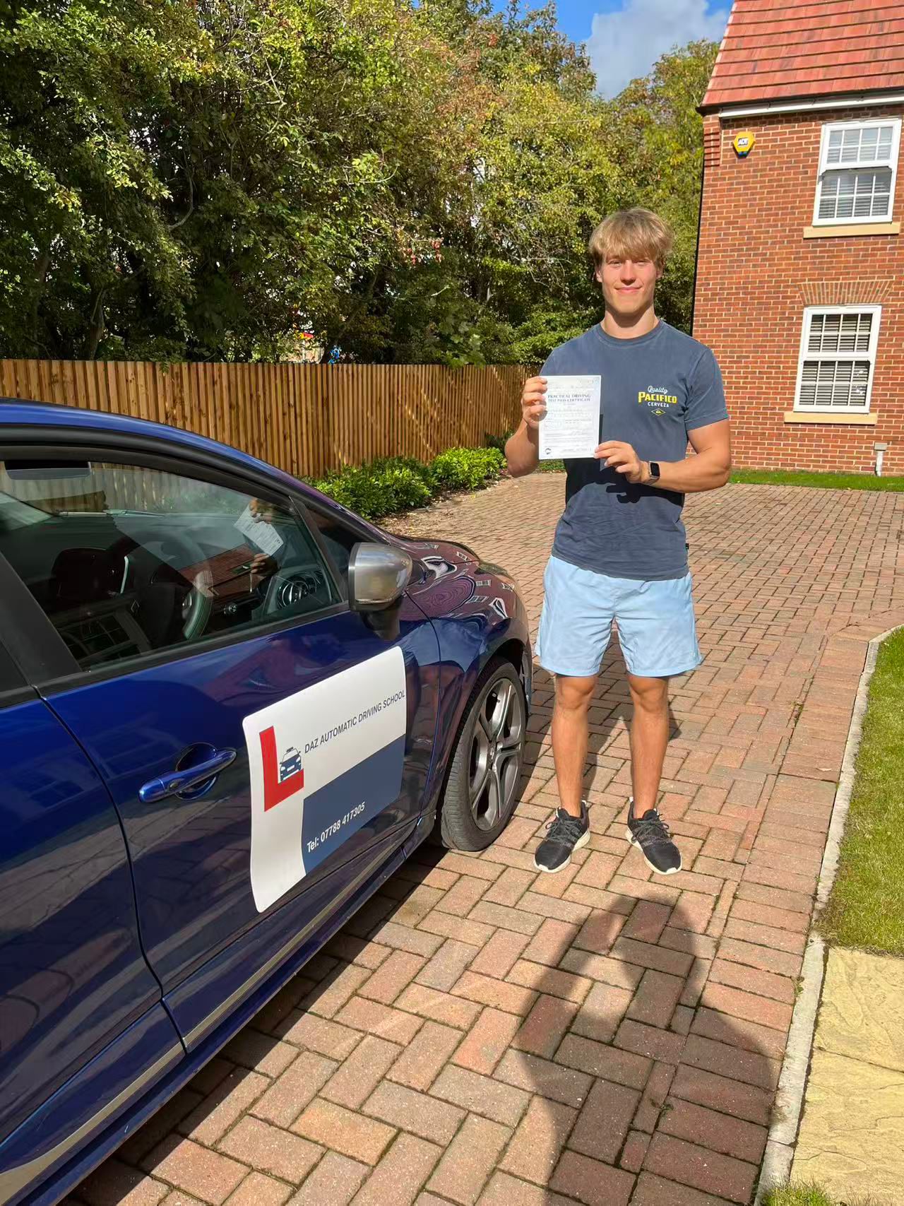 Pupil with pass certificate next to the branded car