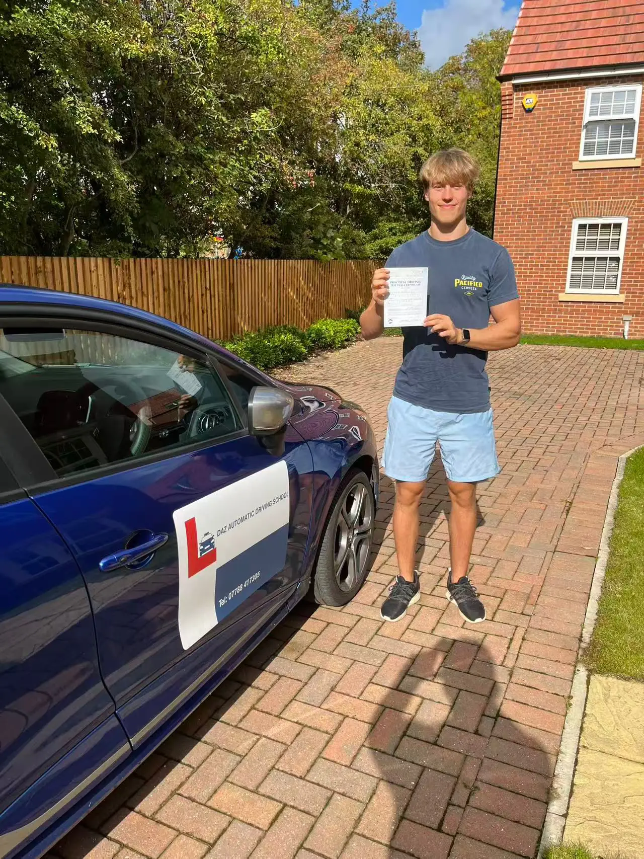 Pupil with pass certificate next to the branded car